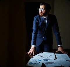 Homem de terno analisando documentos e gráficos sobre uma mesa